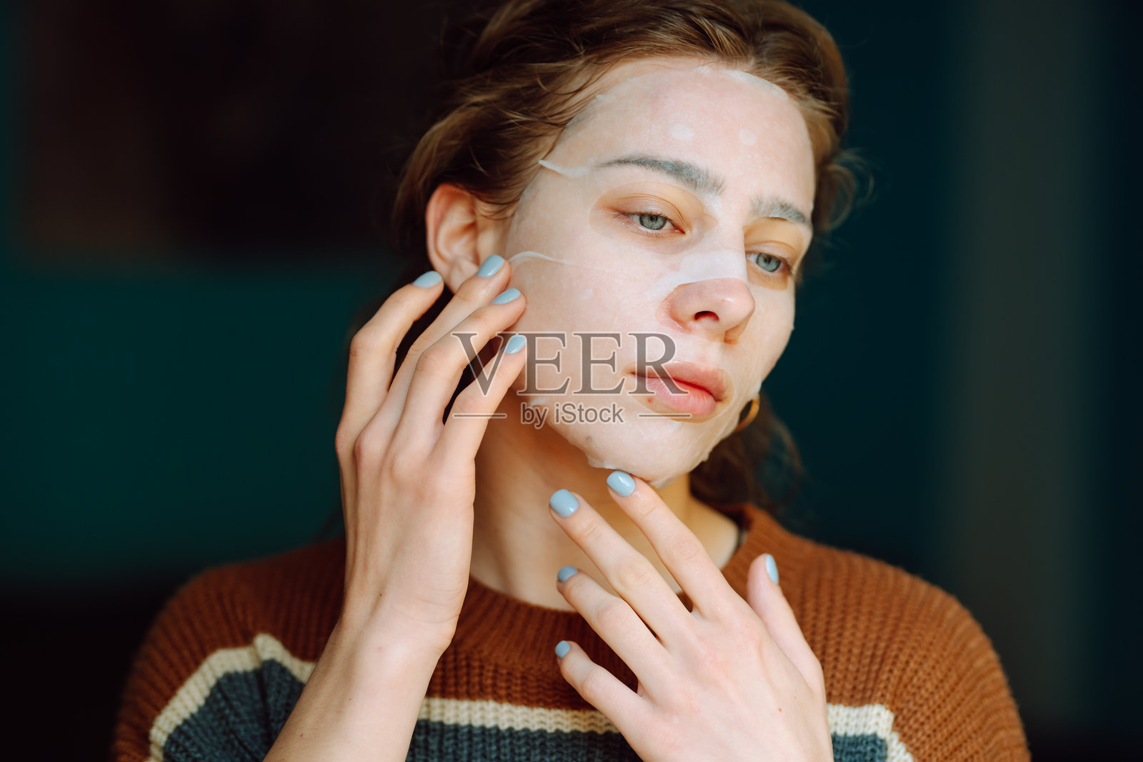 戴着布质口罩的女性在镜子前看着自己的倒影,享受独处的时光。照片摄影图片