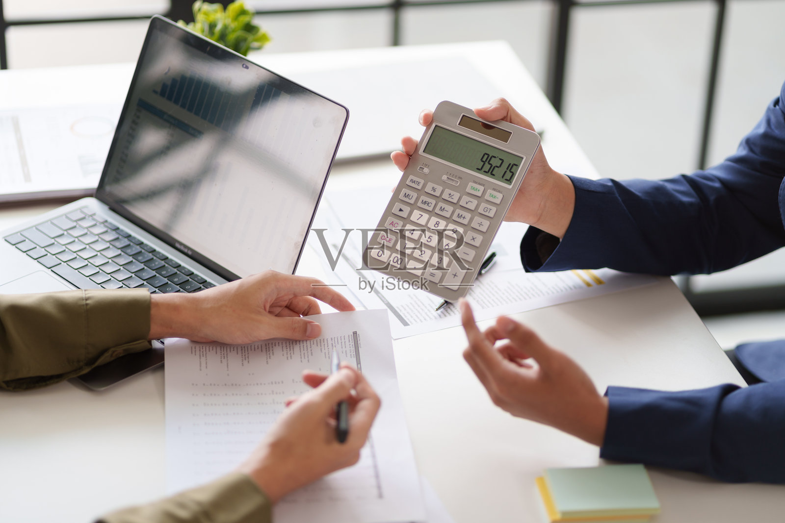 两个人正在进行商务讨论的特写镜头。一人用笔指着,另一人则拿着计算器。照片摄影图片