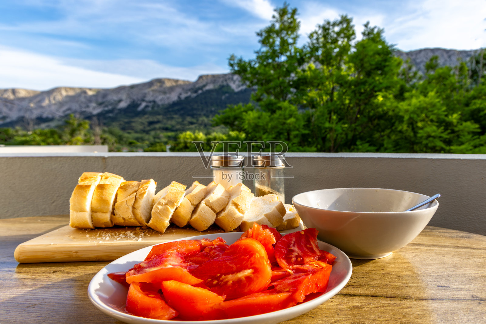 地中海早餐,红色番茄、橄榄油、新鲜面包,摆放在桌子上的盘子里照片摄影图片