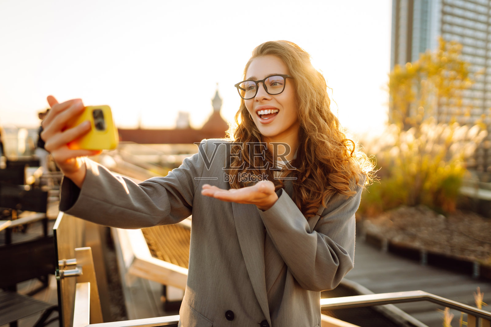 一位美丽的女性在享受日落时用手机自拍。照片摄影图片