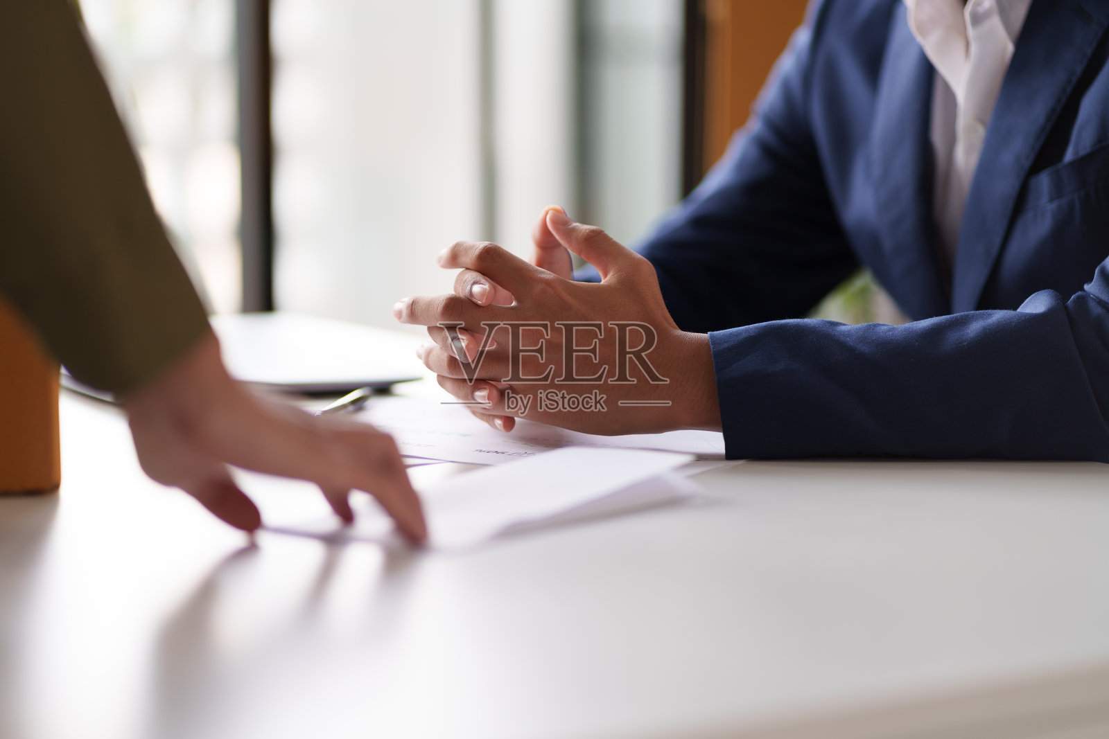 两个人在桌子上交换文件。一个人手里拿着一个装满办公用品的盒子,暗示可能的工作交接或项目转移。照片摄影图片