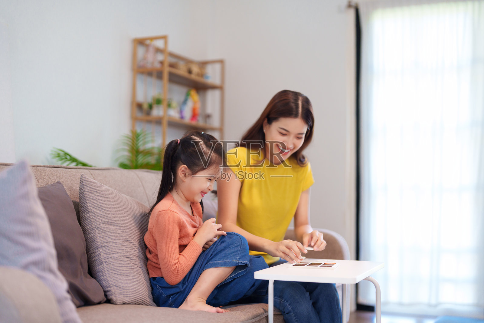 母女俩在桌子上愉快地玩井字游戏,分享欢笑和亲密的时刻。照片摄影图片