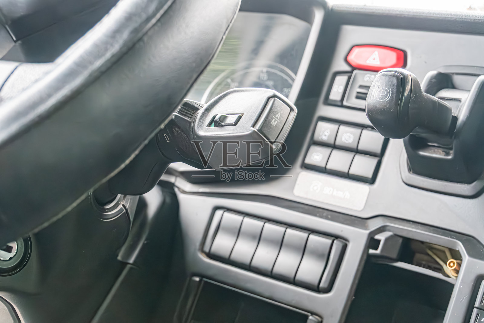 卡车驾驶室内部特写,聚焦于驾驶员区域,包括方向盘、仪表盘和中央控制台。柔和的色调,黑色方向盘与灰米色内饰形成对比。阴天。照片摄影图片