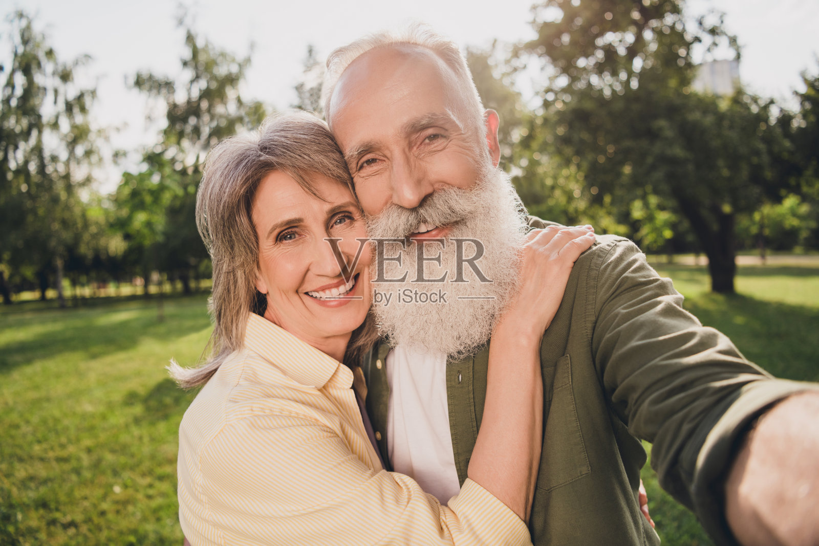 一对有趣的白发老年夫妇在公园户外休息,穿着休闲衬衫自拍。照片摄影图片