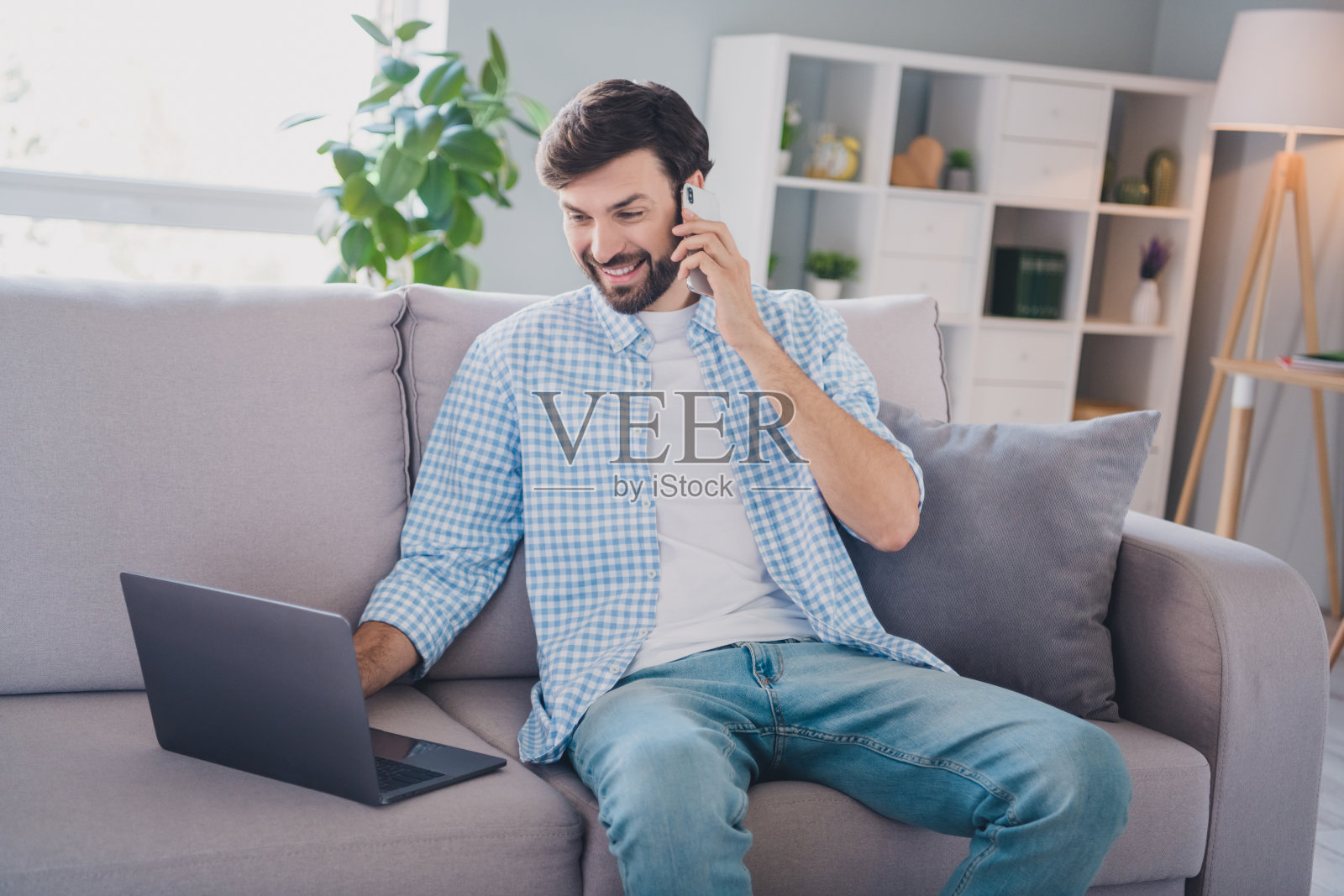 忙碌的商人在家中舒适的室内沙发上隔离工作,穿着休闲服装进行远程工作。照片摄影图片