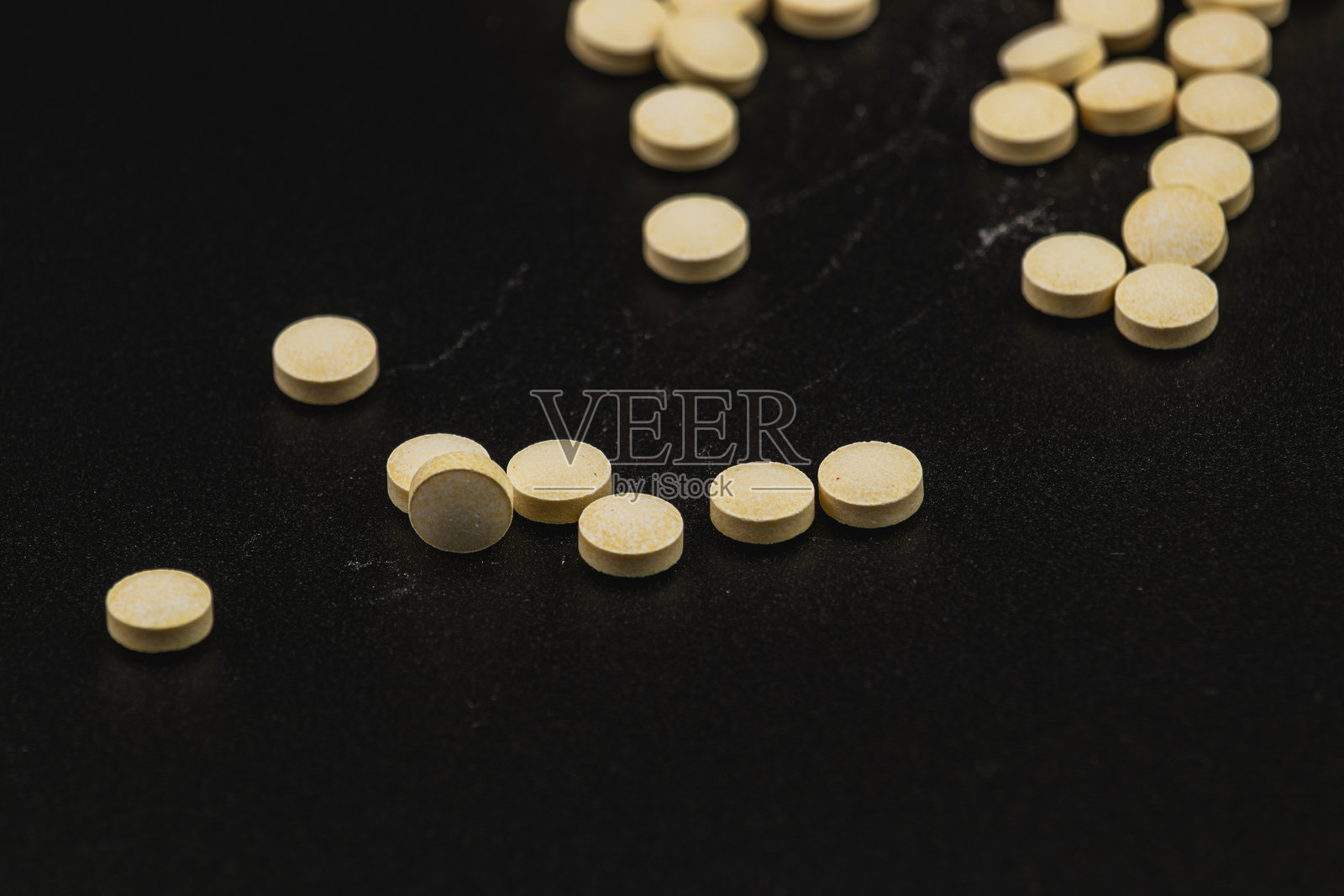 在临床环境中,散落在黑色表面上的黄色药片照片摄影图片