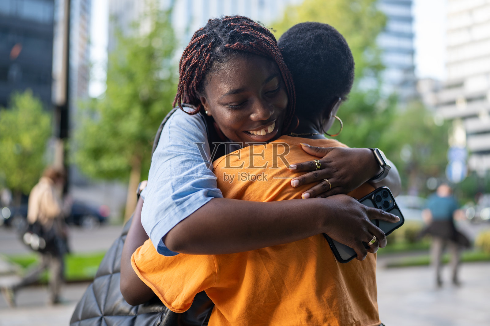 快乐的非裔美国女性在街上相拥而笑,幸福地微笑和大笑。照片摄影图片