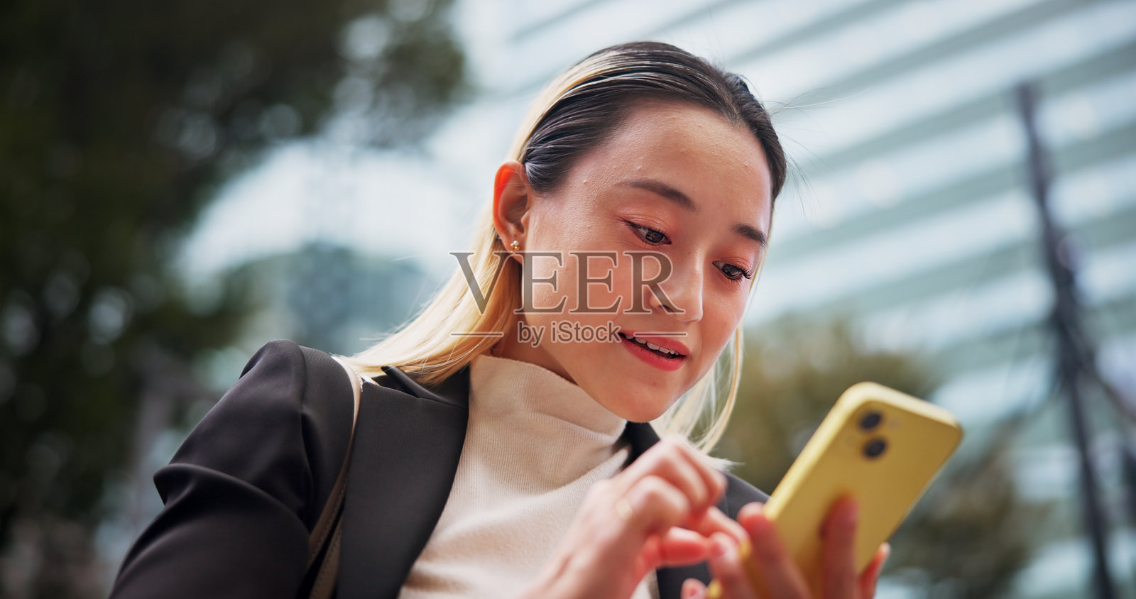 商务女性在城市中发短信,阅读和建立法律职业网络。她是一位快乐的企业律师,手持智能手机,接收通知、交易或旅行信息,地点在日本。照片摄影图片