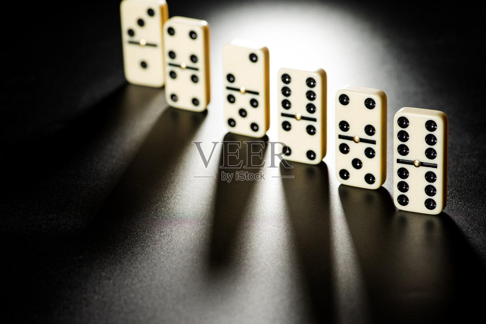 多米诺骨牌,美丽的白色骨牌小心地放置在黑色表面上,选择性对焦。照片摄影图片