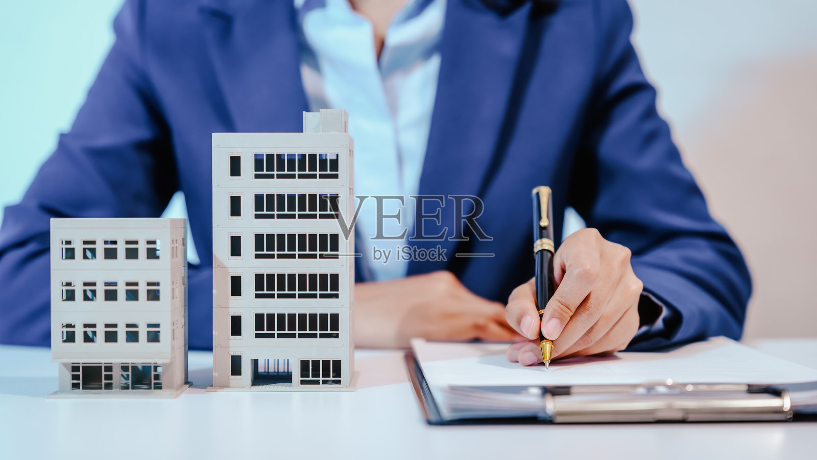 一名女性员工在房地产办公室的桌子上工作,管理城市的公寓销售。她与客户沟通,处理房源,并提供有关可用物业的信息。照片摄影图片