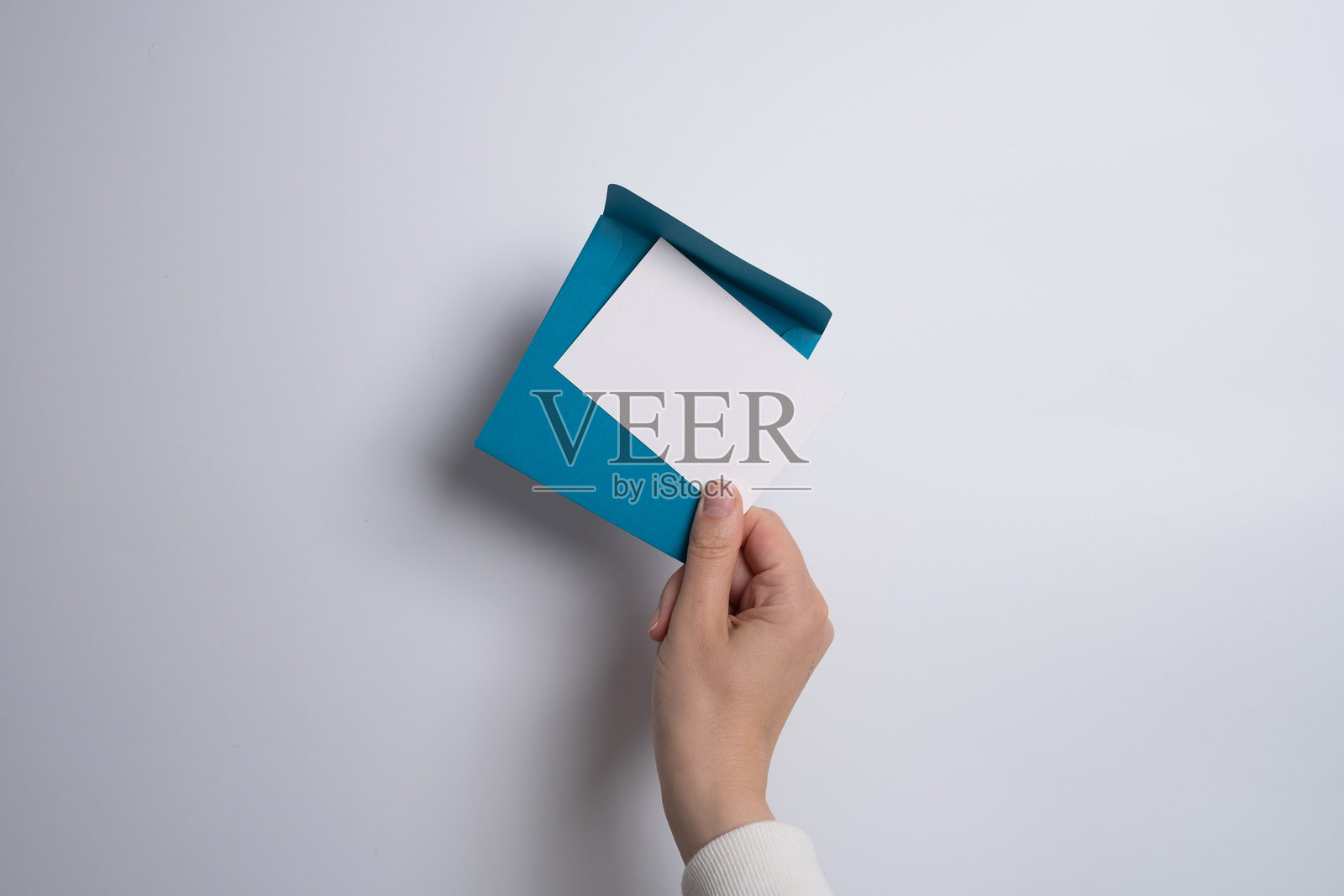 女孩坐在沙发上,手中拿着一张节日贺卡。纸上有可爱的邀请信息。留有空白供填写文本。照片摄影图片