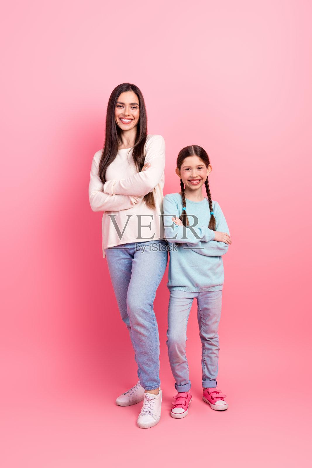 快乐的母女在粉色竖直背景前摆姿势,展现家庭的亲密和爱。照片摄影图片