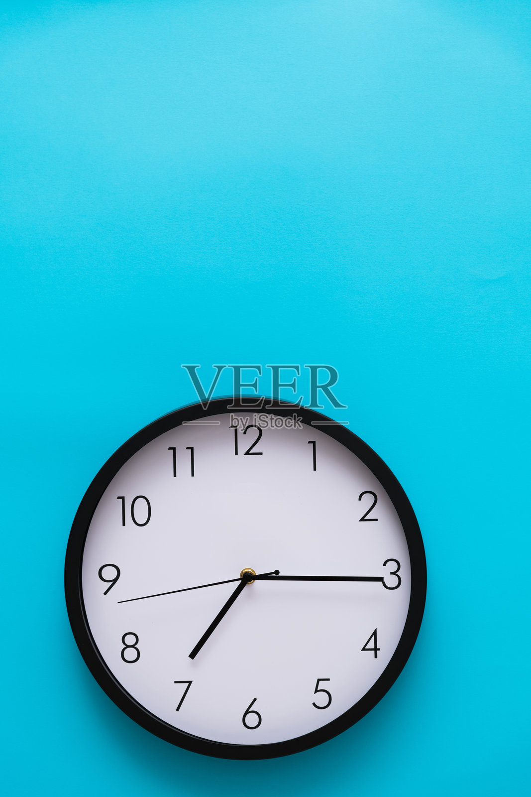 蓝色背景上的黑色墙钟照片摄影图片