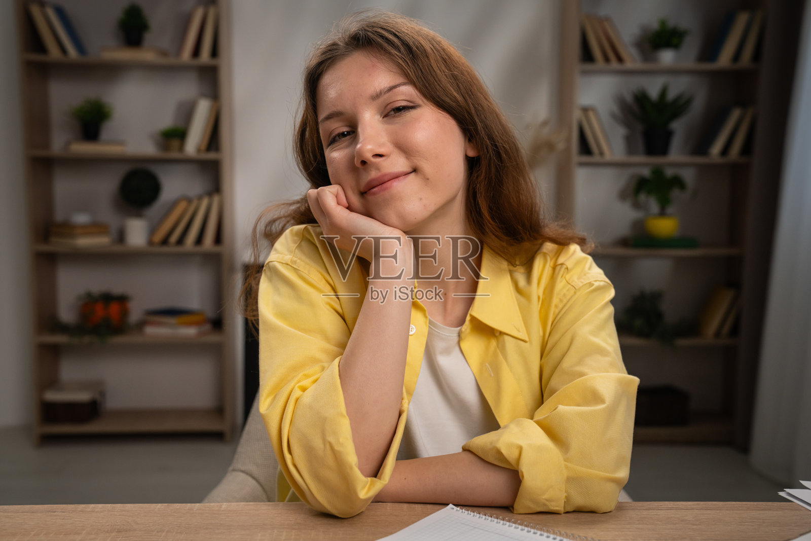 穿着黄色衬衫的微笑女性在舒适的家庭办公室放松照片摄影图片