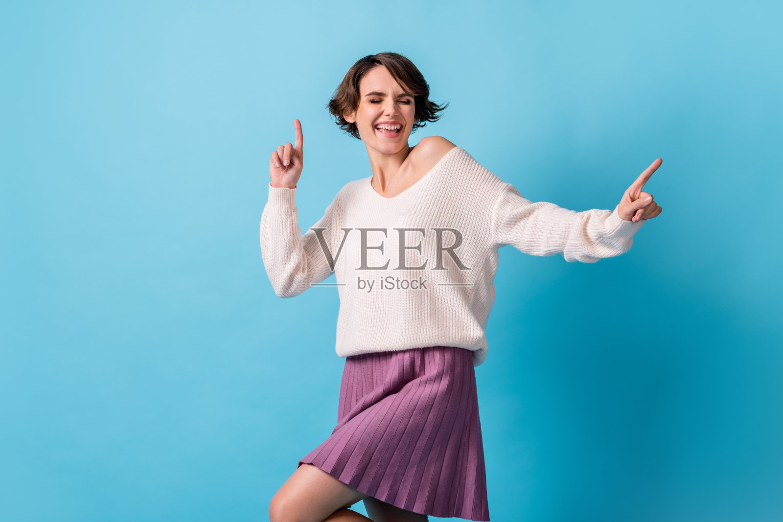 年轻快乐兴奋的女孩,开心地微笑,享受舞蹈,背景为蓝色。照片摄影图片