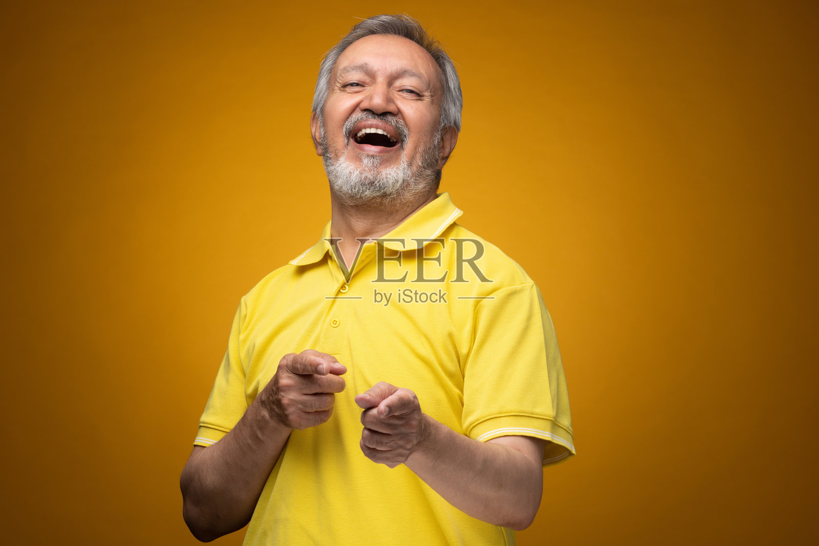 穿着黄色T恤的老年帅气男性肖像照片,背景为黄色。照片摄影图片