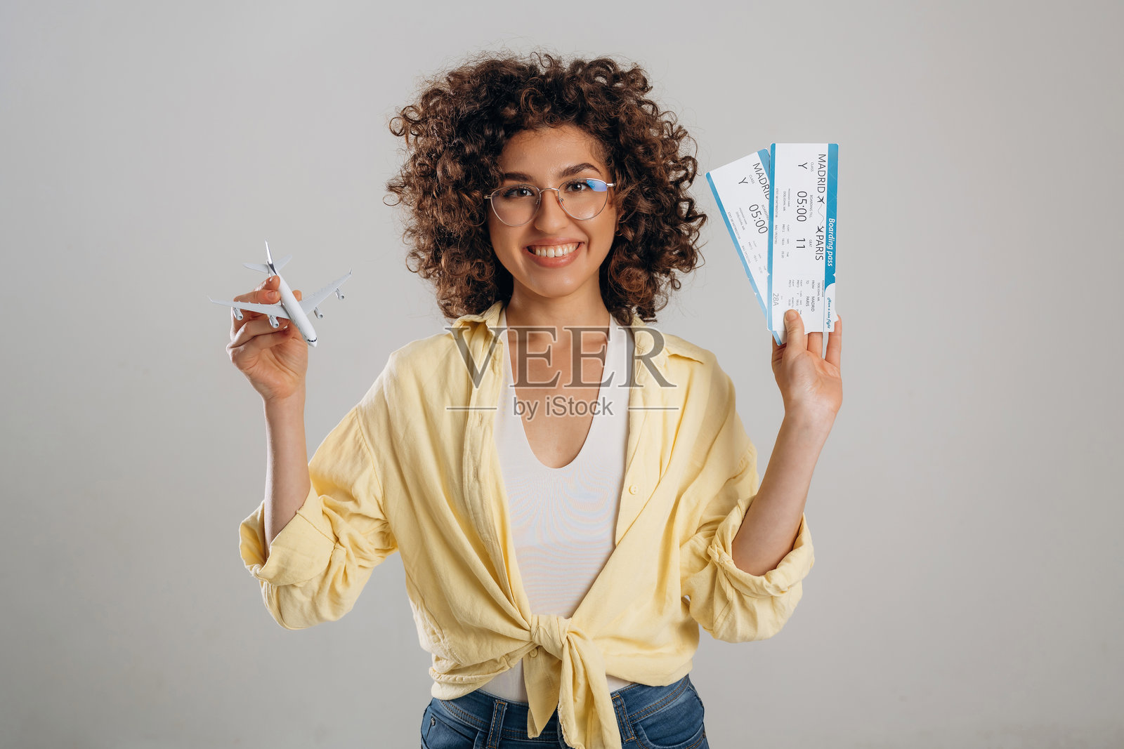 手中拿着两张票和一架玩具飞机。美丽的女人在工作室里。照片摄影图片