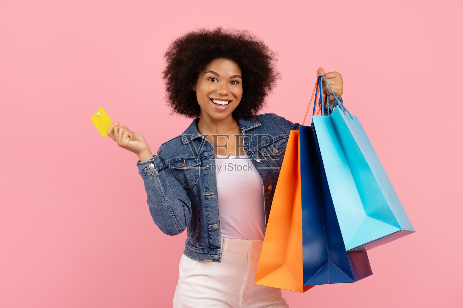 年轻黑人女性手持五彩购物袋和黄色信用卡的肖像照片摄影图片