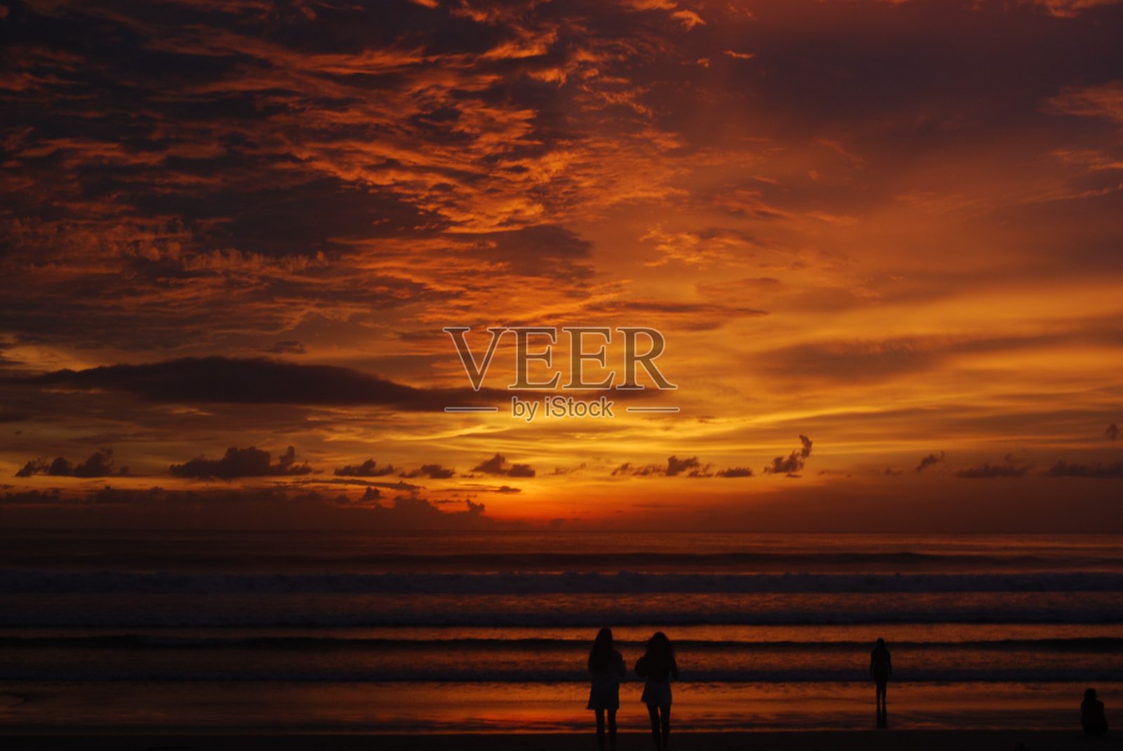 图像捕捉到海洋上方壮观的日落,女孩的剪影映入眼帘。照片摄影图片