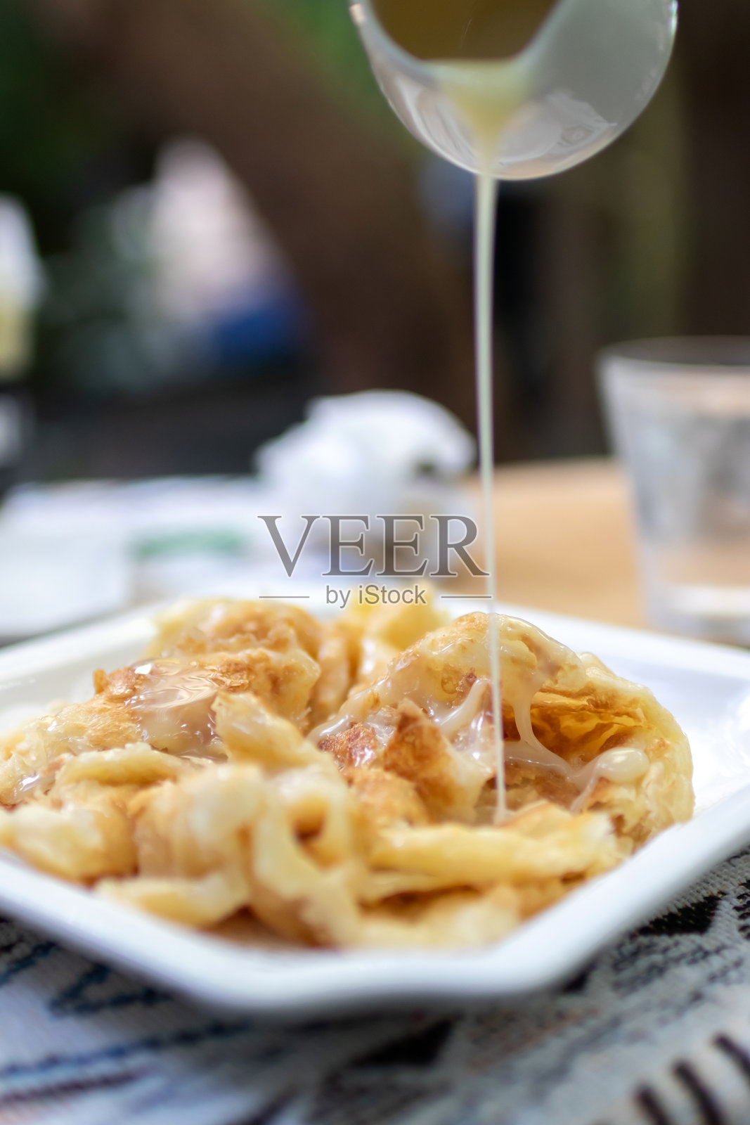 泰国受欢迎的街头小吃:涂抹甜炼乳的印度薄饼。照片摄影图片