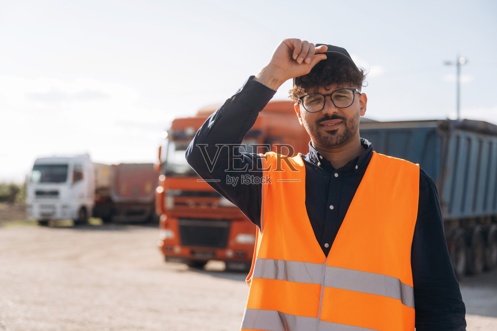 穿着橙色制服的男性工人在户外靠近卡车。照片摄影图片