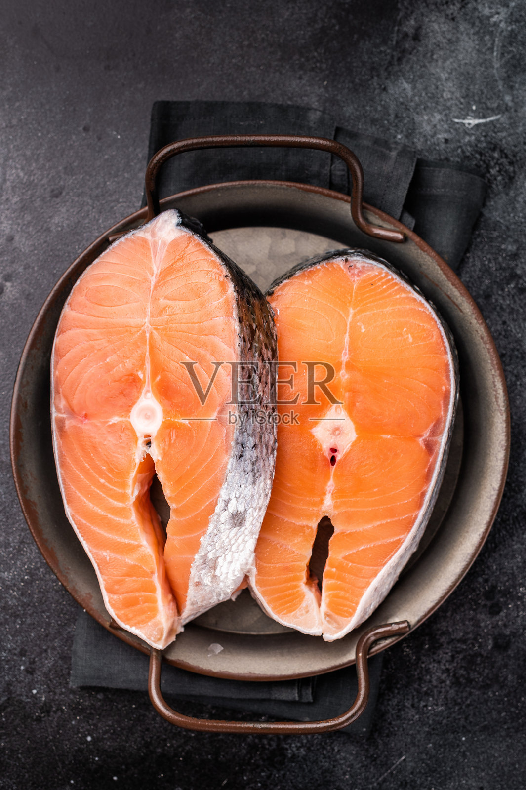 新鲜生三文鱼片,闪烁着水分,准备腌制或烤制。健康海鲜爱好者的完美选择。黑色背景。俯视图。照片摄影图片