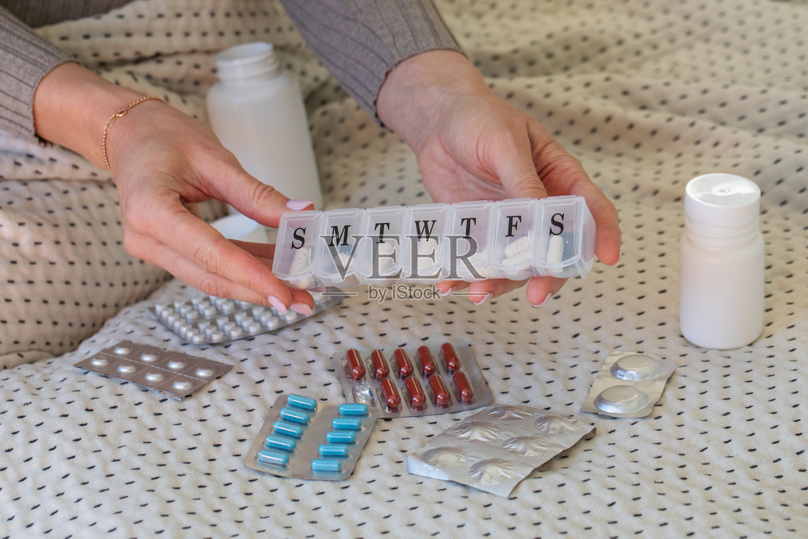 女性手握着装有药丸的每周药物整理盒。药物与治疗照片摄影图片