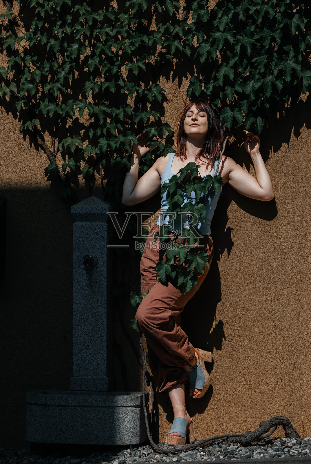 年轻的白人女性在阳光下与绿叶背景合影照片摄影图片