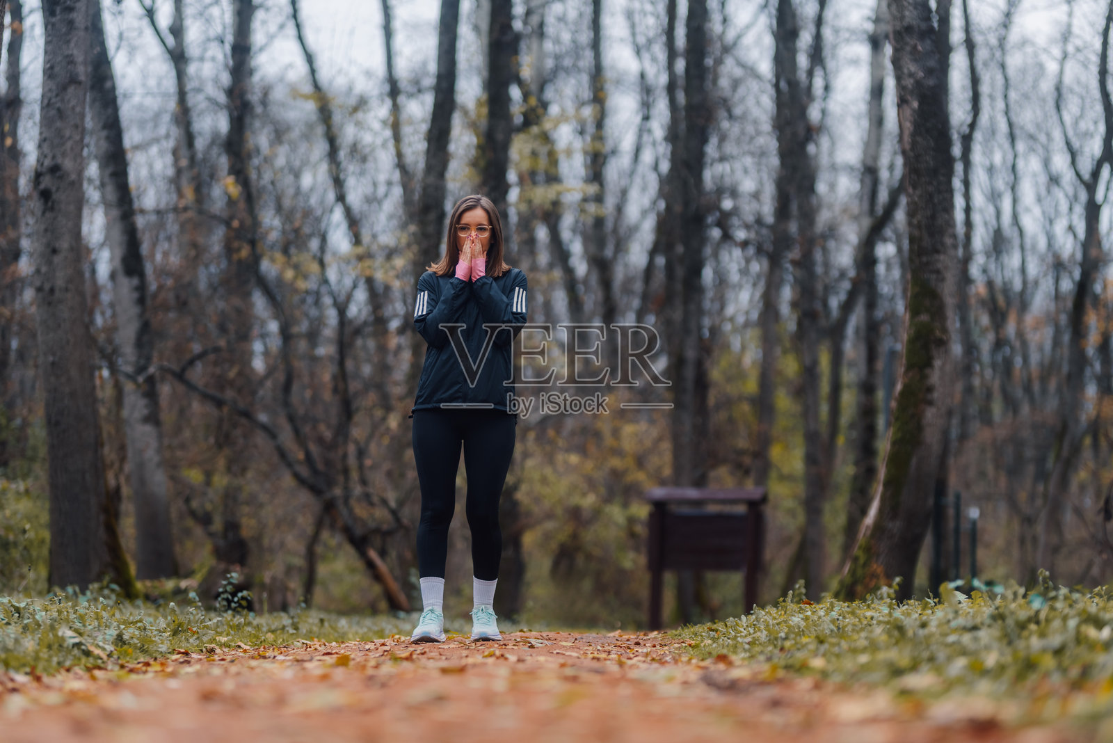 年轻女性在寒冷的秋季公园里热身,深呼吸。照片摄影图片