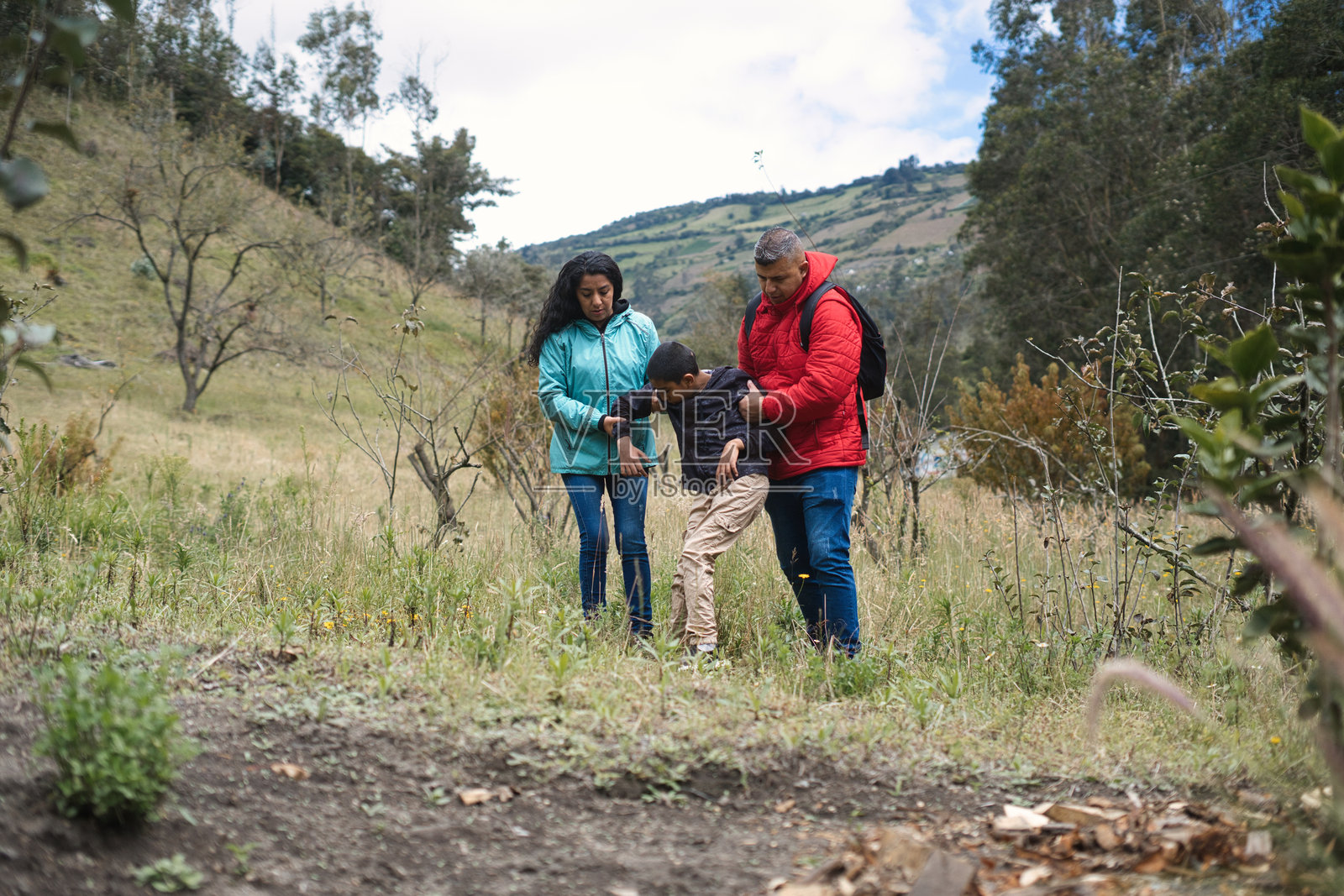 父母在乡间徒步旅行时帮助他们的青少年儿子照片摄影图片