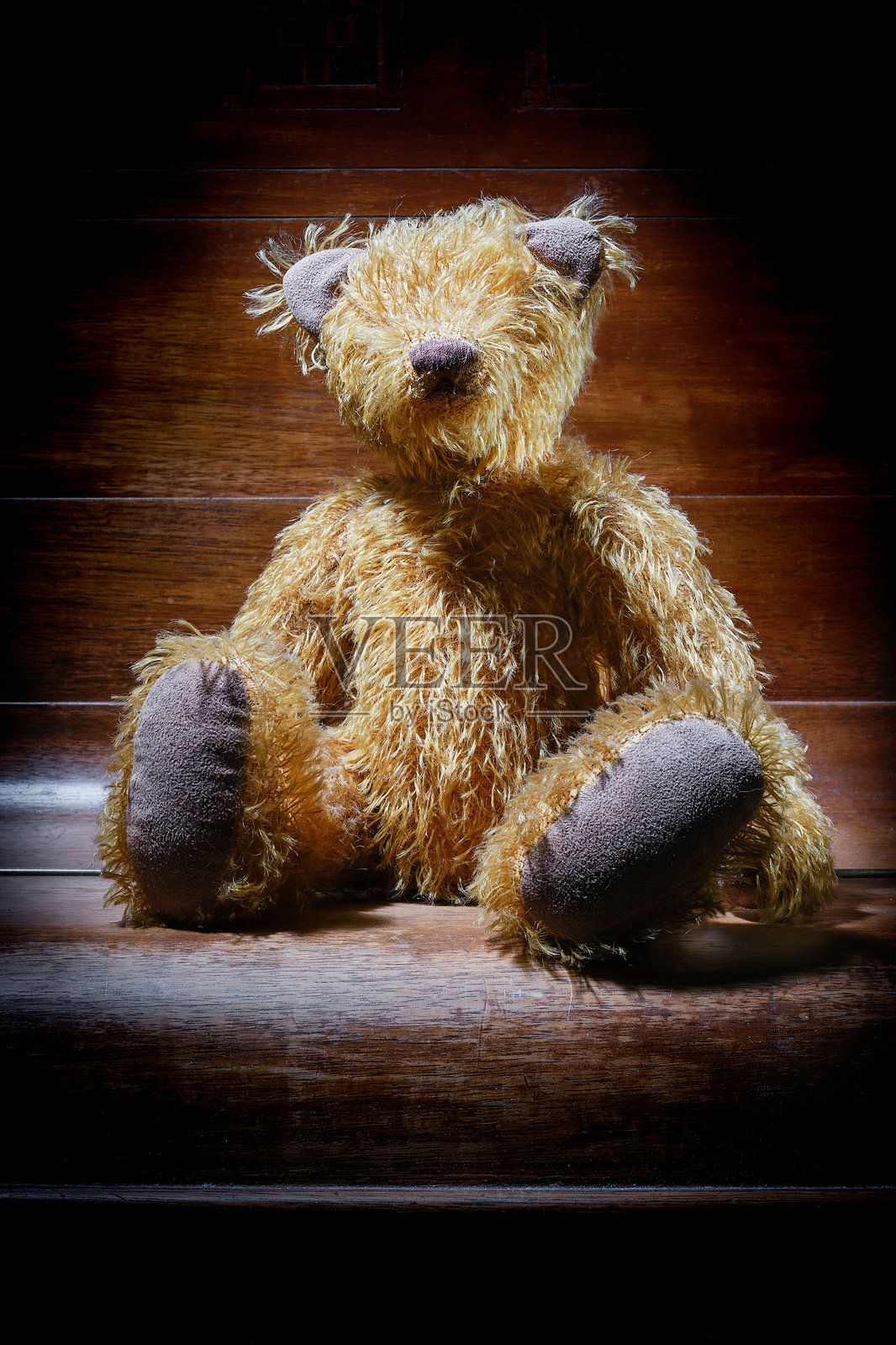 黄色泰迪熊坐在一架关闭的钢琴盖上。照片摄影图片