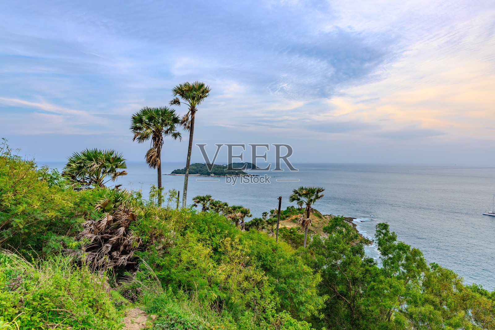 普罗姆提普角的日落,俯瞰奈汉海滩,海岸附近有一个小岛——科曼岛,位于泰国普吉岛。郁郁葱葱的绿树和安达曼海的碧绿海水。照片摄影图片