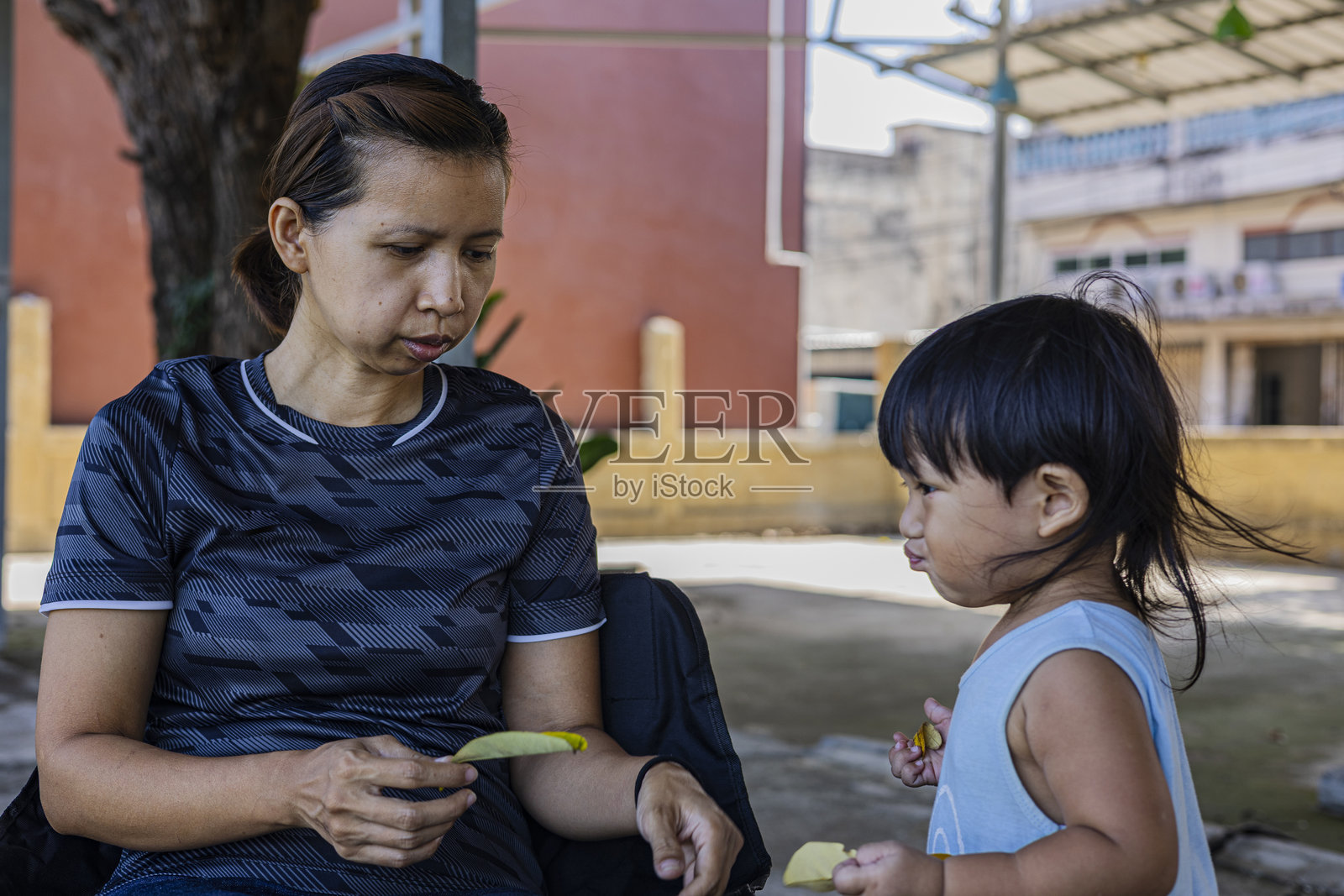 幼儿为妈妈收集干树叶照片摄影图片
