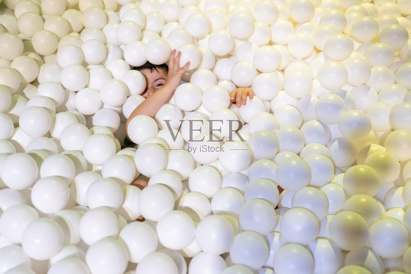 孩子在充满白色球的球池中享受玩耍时光照片摄影图片