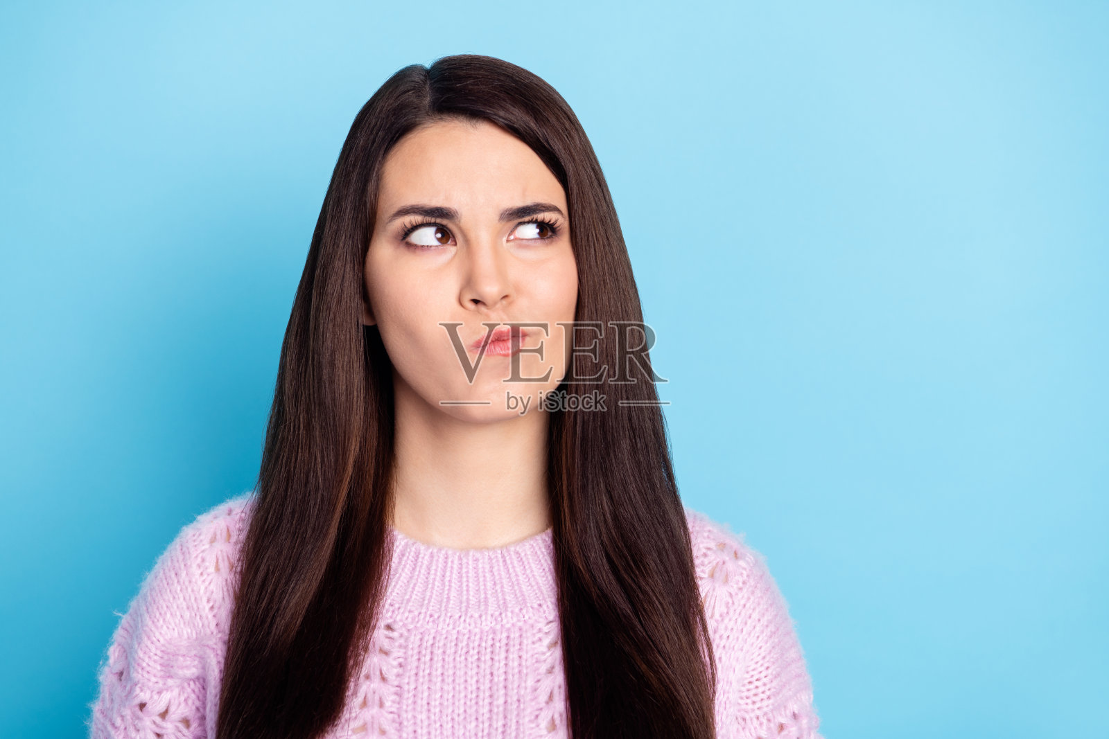 年轻女性认真思考,深思熟虑,创意构思,凝视空旷空间,背景为蓝色。照片摄影图片