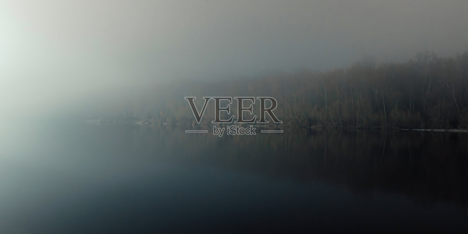 夜晚的雾霭河岸,远处的灯光照亮,水面平静,四周昏暗。照片摄影图片