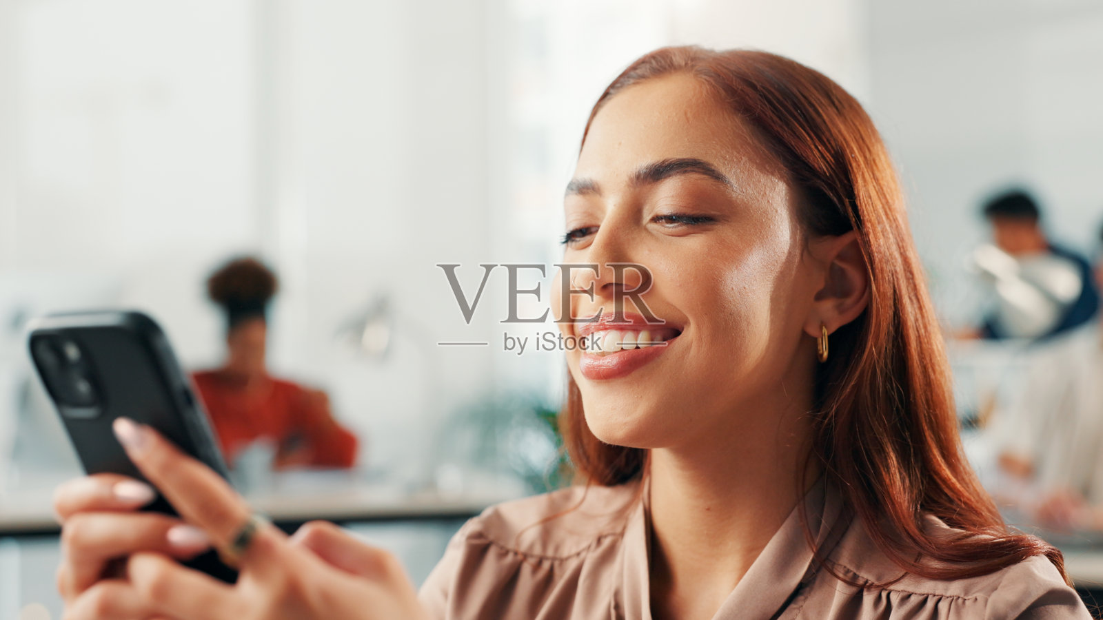 商务女性在办公室用手机打字,发送短信、编辑电子邮件或阅读在线新闻。记者在工作间隙使用智能手机滚动社交媒体或查看出版日程。照片摄影图片