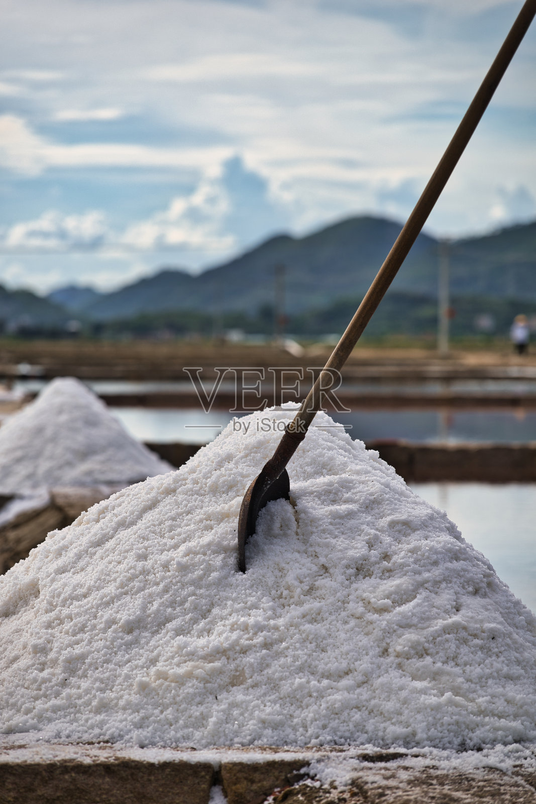 盐田里一堆盐,旁边插着一把铲子照片摄影图片