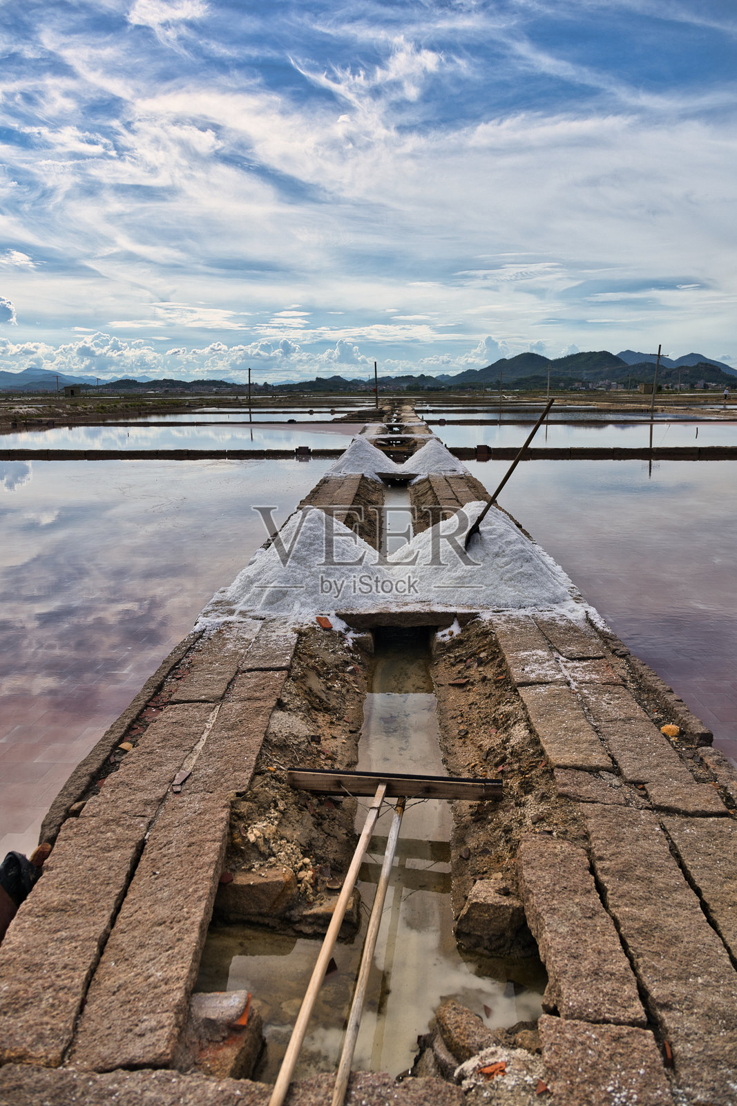宁静天空下盐池中的古老石渠照片摄影图片
