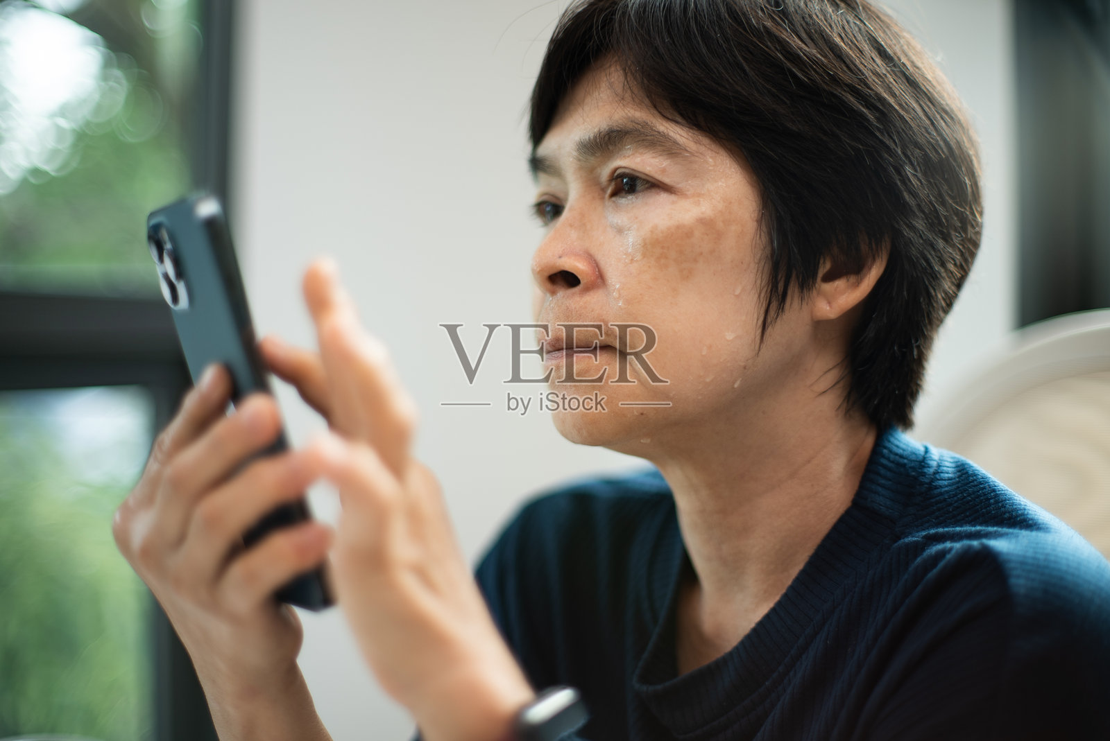 成熟的女性在使用智能手机时经历潮热。照片摄影图片