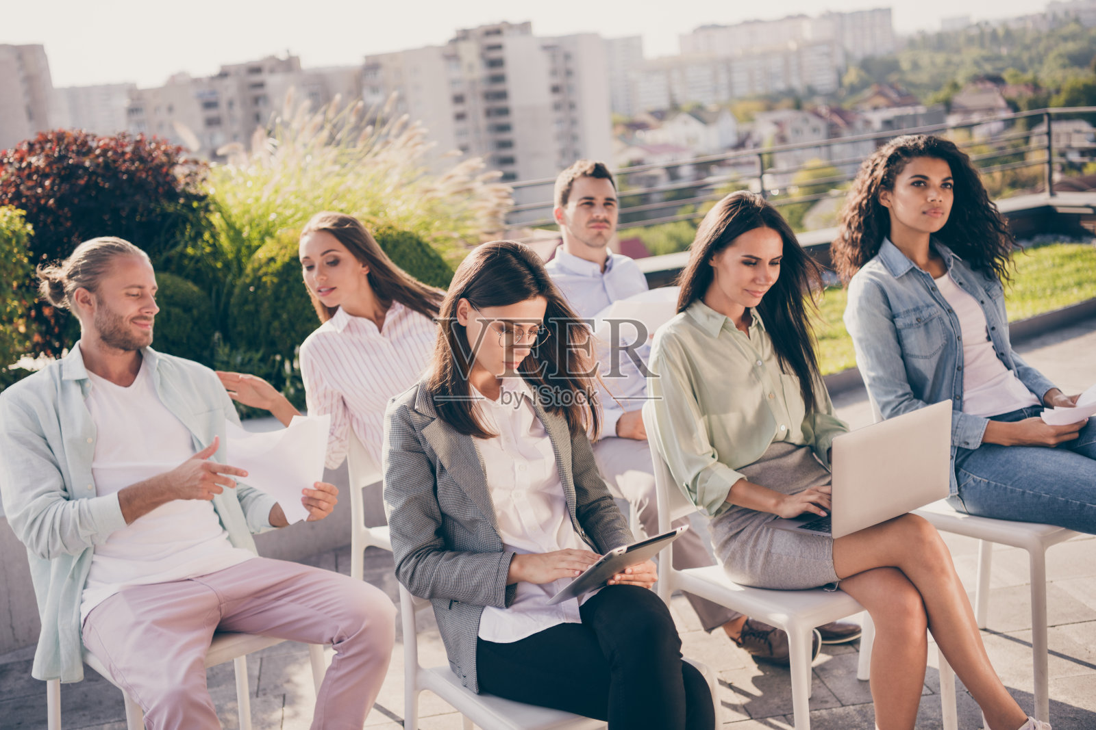 年轻同事们在户外开会,使用笔记本电脑,相互交流和讨论。照片摄影图片