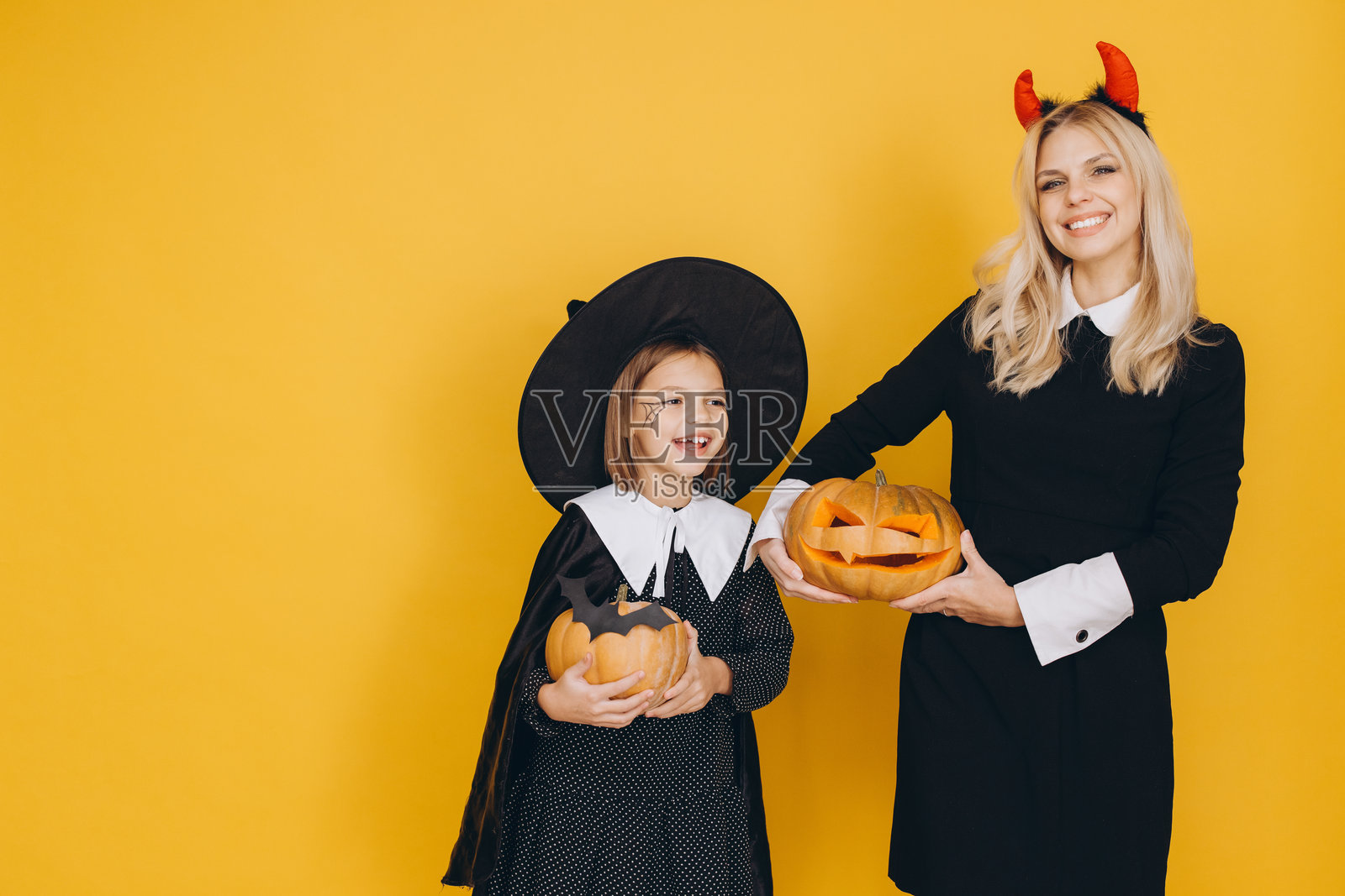 母女俩在万圣节派对上微笑着手持雕刻的南瓜照片摄影图片