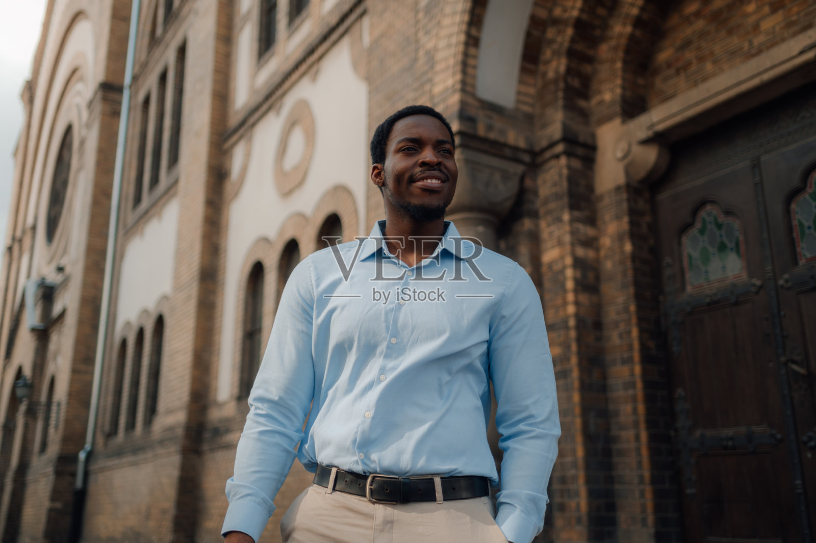 自信的商人在城市教堂外微笑照片摄影图片