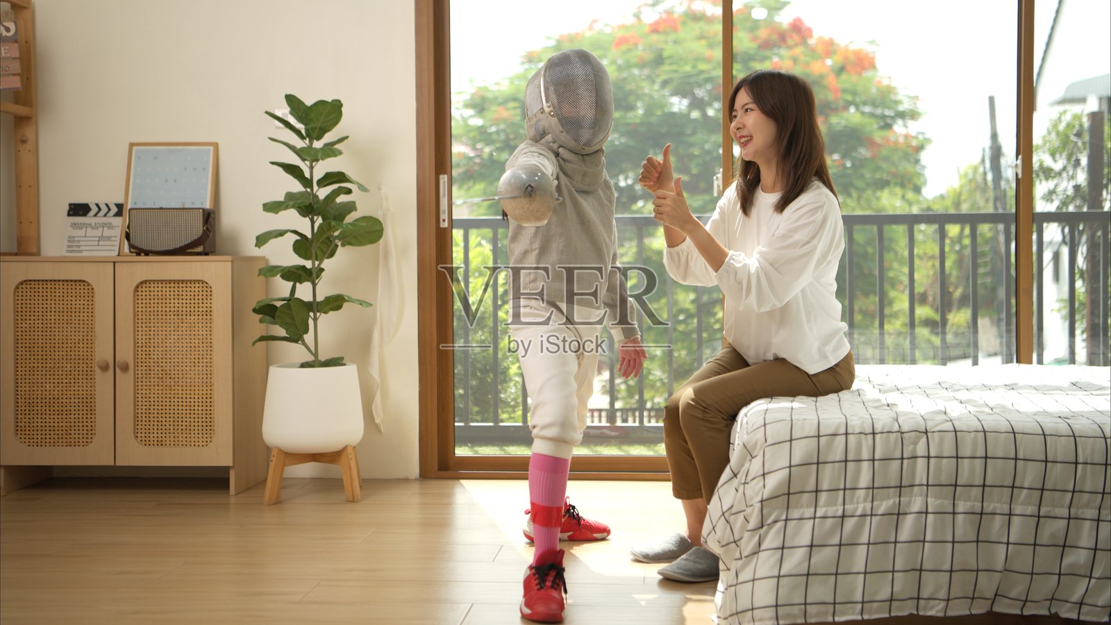 一个穿着击剑装备的女孩和她的母亲在准备食物和运动器材,为即将到来的比赛日进行击剑练习。照片摄影图片