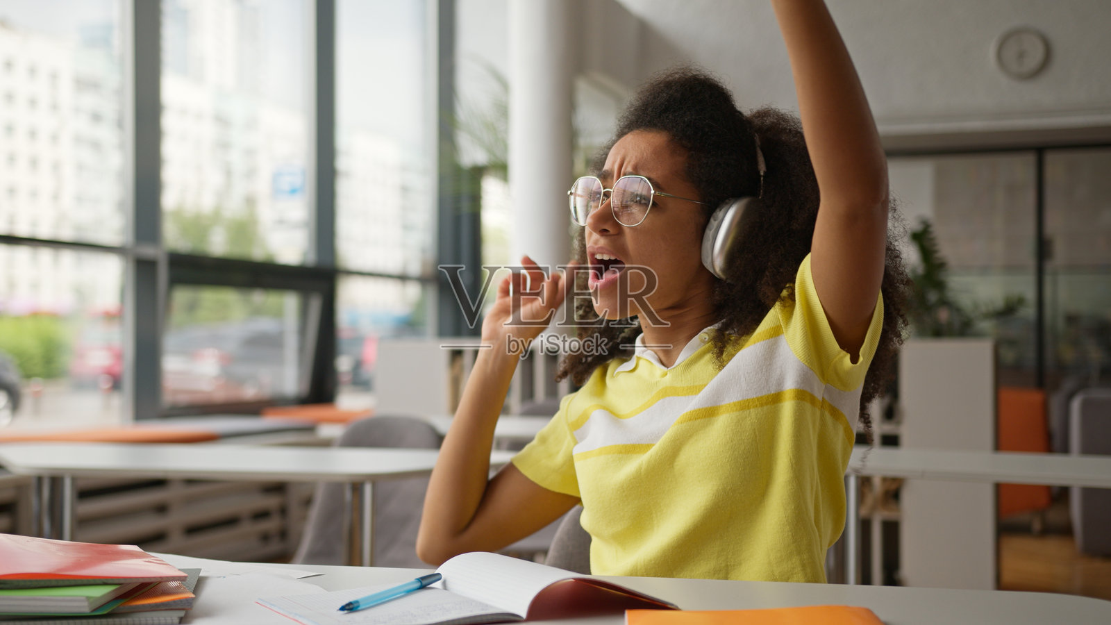 快乐搞笑的非裔美国女孩,女学生,商务女性,戴着耳机,享受无线音频,在咖啡馆、学校、大学图书馆学习时暂停。照片摄影图片