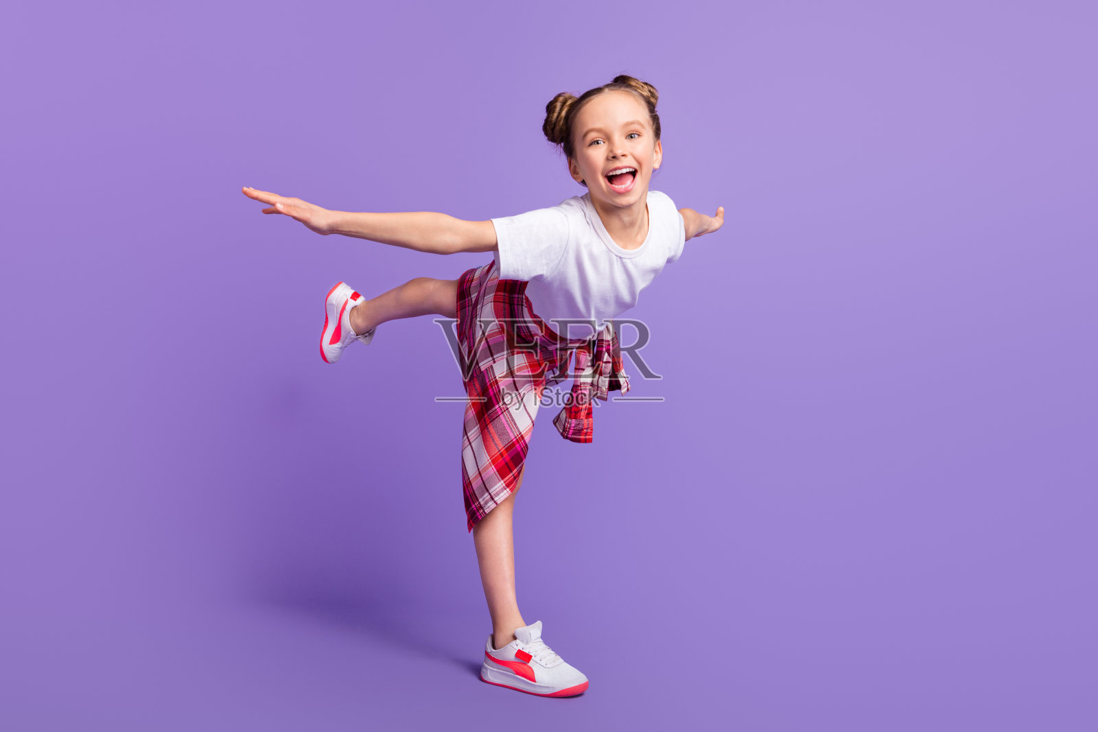 全身侧面照,快乐的学生双臂张开,面向镜头,衬衫系在腰间,背景为紫色。照片摄影图片