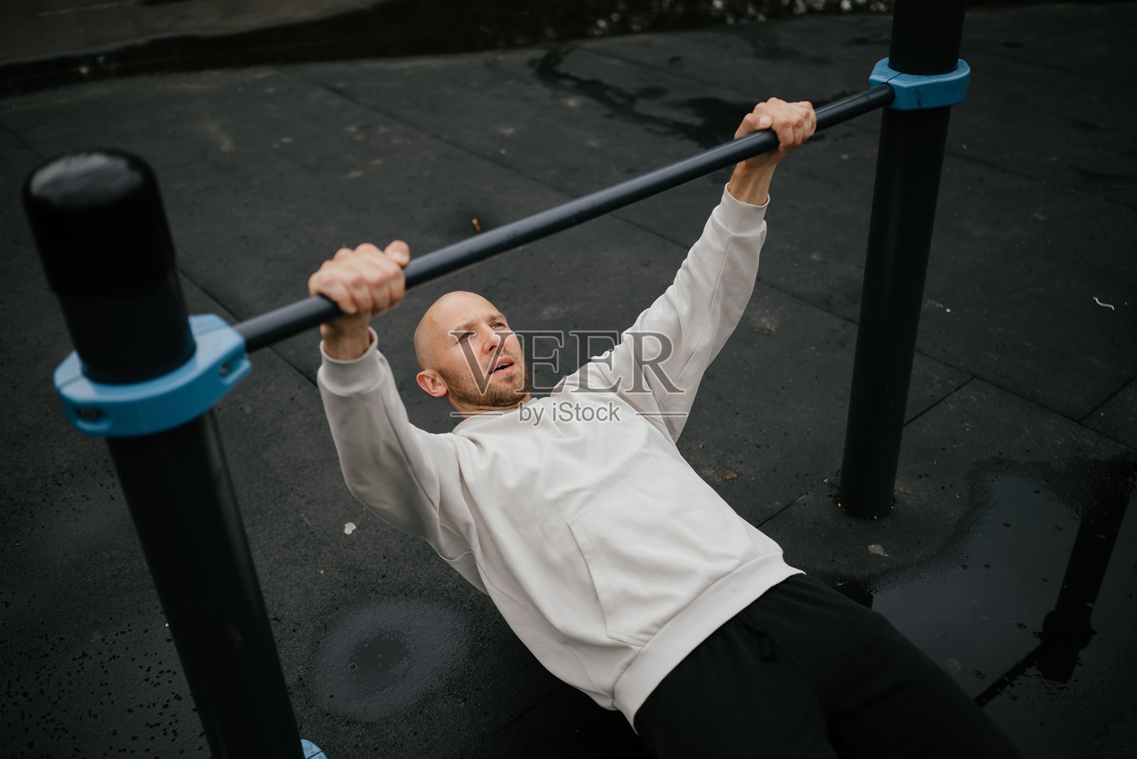 在户外的横杆上进行引体向上锻炼的男子照片摄影图片