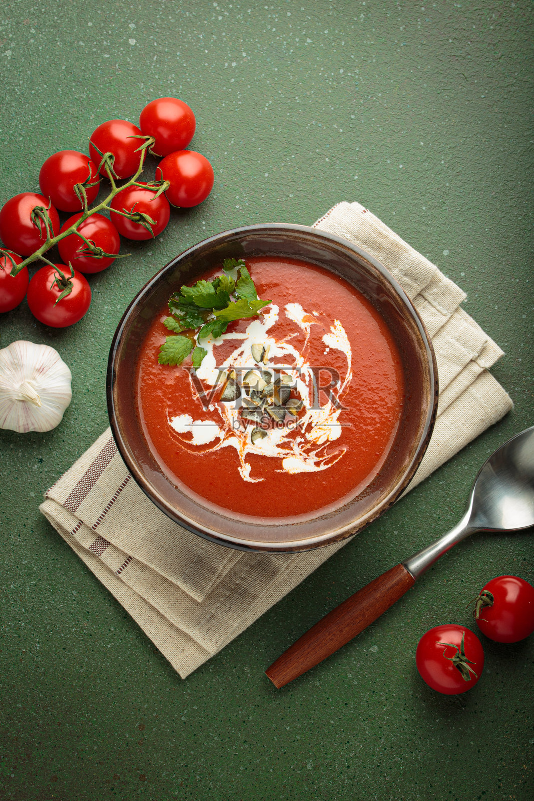 绿色背景上方视角的奶油番茄汤,配有南瓜籽和香草照片摄影图片