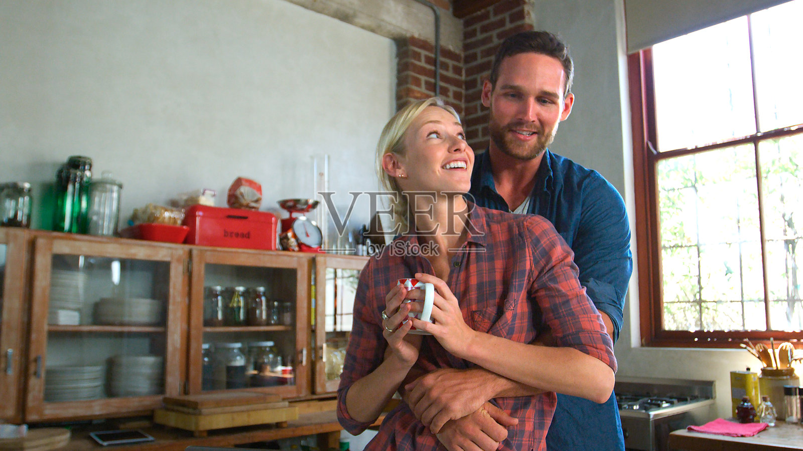 年轻情侣在开放式公寓厨房中相拥而抱照片摄影图片