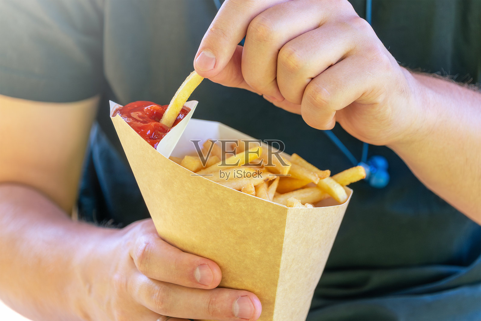 男性手将薯条浸入番茄酱中照片摄影图片